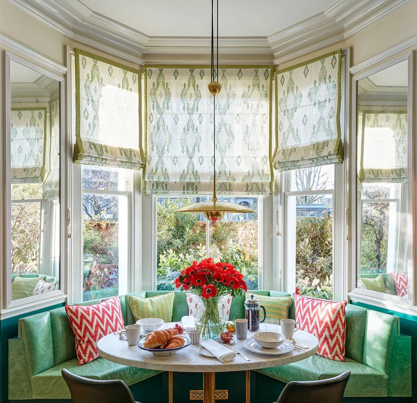 Bright kitchen nook with banquette and sheer roman blinds in bay window