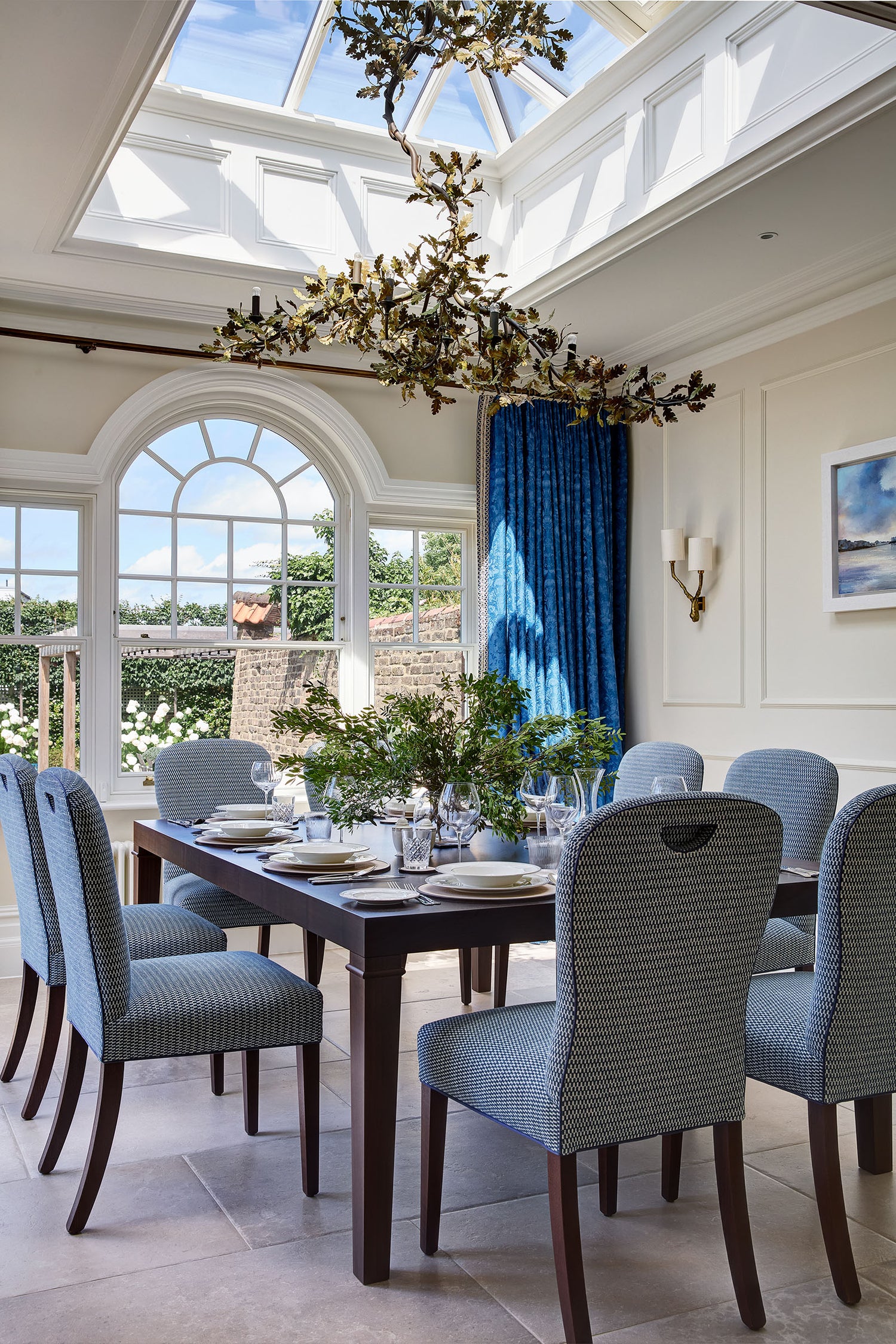 A fantastic dining room with large skylight and chandelier, with a rich blue curtain and bronze curtain rail