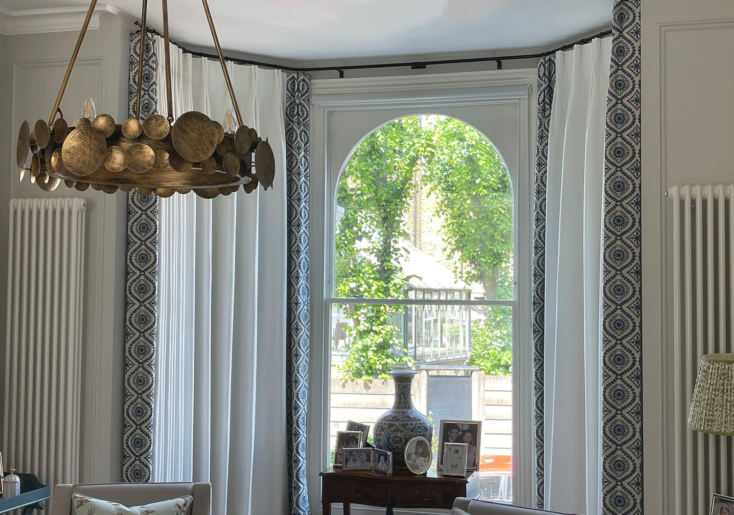 Detail of bay window curtains on thin bronze pole showing double pleat heading in Richmond